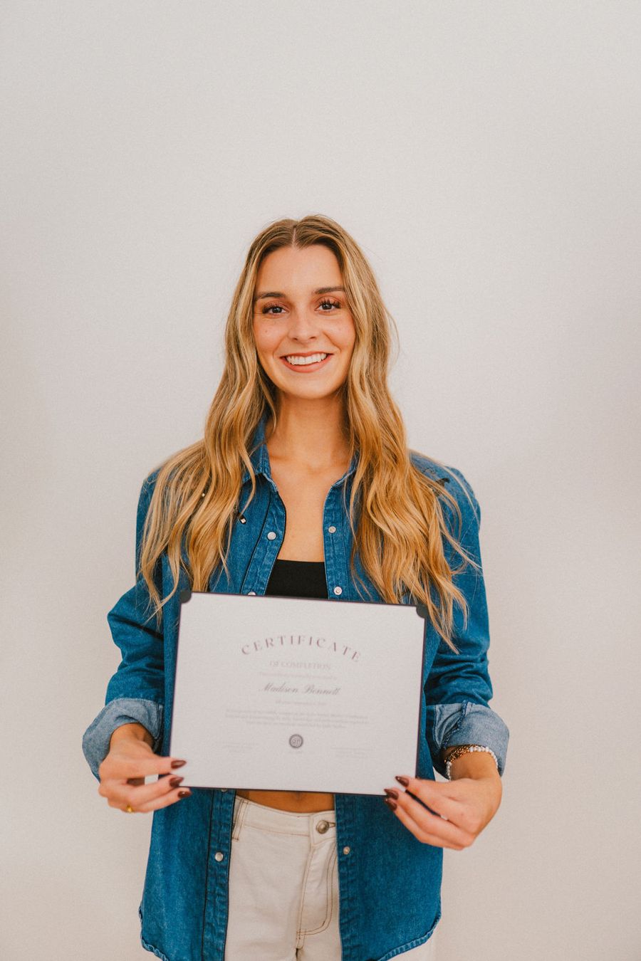 A certified NSTPA spray tan professional holding her certificate